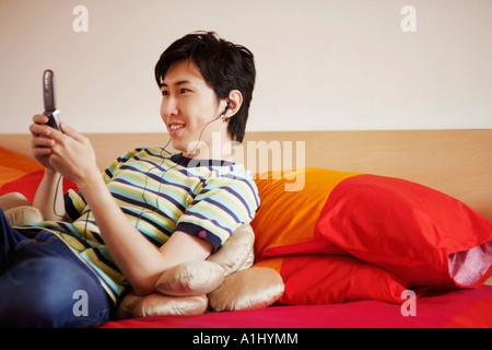 Close-up of a young man listening to music and reclining on the bed Stock Photo