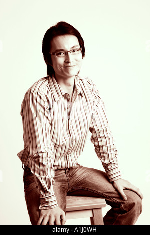 Portrait of a mid adult man sitting on a stool and smiling Stock Photo