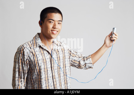 Portrait of a young man wearing headphones and holding a mobile phone Stock Photo