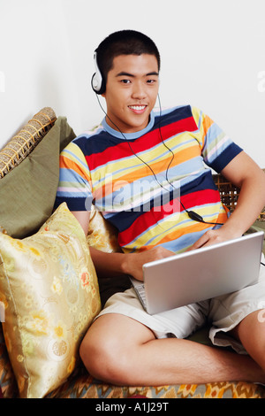 Portrait of a young man listening to music and using a laptop Stock Photo