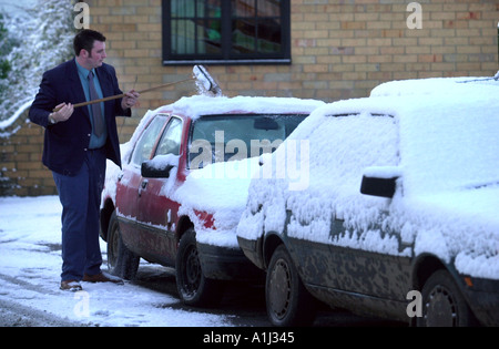 BRUSHING SNOW OFF A CAR BEFORE GOING TO WORK IN THE MORNING UK Stock Photo