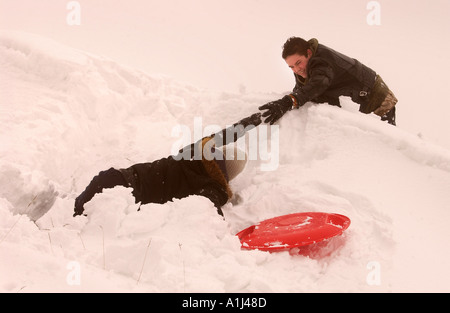 BOYS PLAYING IN A SNOW DRIFT ON CLEEVE HILL NEAR CHELTENHAM UK Stock Photo