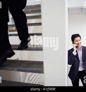 Low section view of a man walking down stairs with another businessman talking on a mobile phone Stock Photo