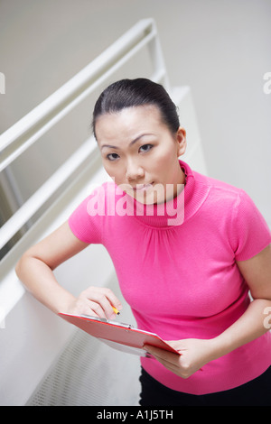 Portrait of a businesswoman standing on a staircase and holding a clipboard Stock Photo