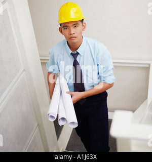 Portrait of an architect walking down stairs and carrying blueprints Stock Photo