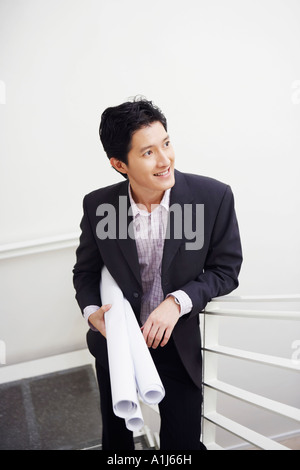Businessman walking up stairs and carrying blueprints Stock Photo