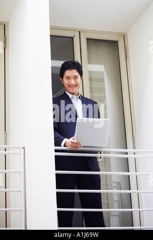 Portrait of a businessman standing at the doorway of an office and using a laptop Stock Photo