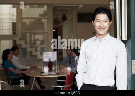 Portrait of a businessman leaning against a door and smiling Stock Photo