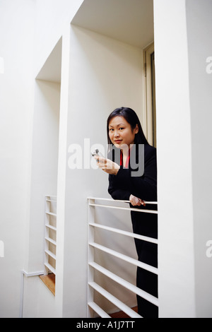 Portrait of a businesswoman leaning over a railing and holding a mobile phone Stock Photo