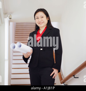 Low angle view of a businesswoman holding rolled up charts and smiling Stock Photo