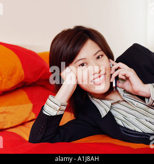 Portrait of a businesswoman lying on the bed and talking on a mobile phone Stock Photo