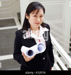Portrait of a female architect holding rolled up blueprints and smiling Stock Photo