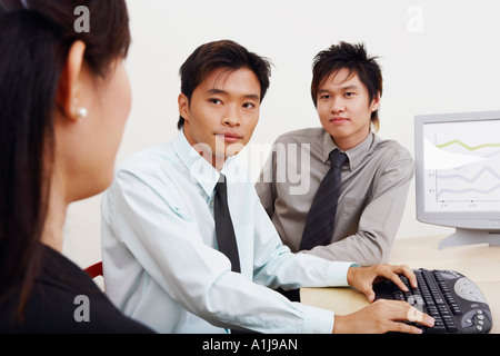 Two businessmen and a businesswoman sitting together in an office Stock Photo