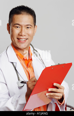 Portrait of a male doctor writing on a clipboard and smiling Stock Photo