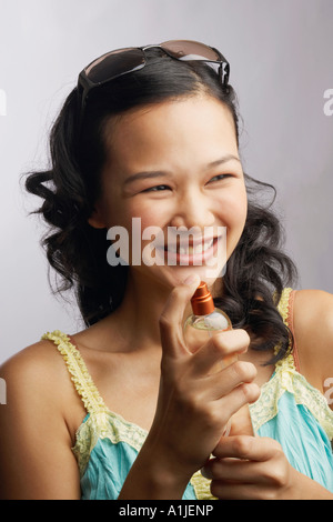 Close-up of a young woman holding a bottle of perfume and smiling Stock Photo