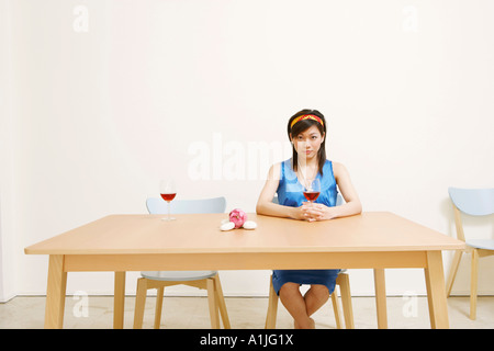 Portrait of a young woman holding a glass of wine and sitting on a chair Stock Photo