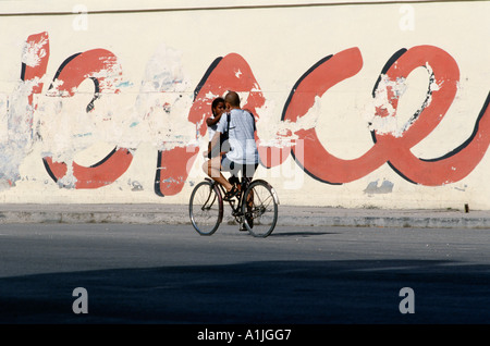 Havana Cuba Lovers on a bicycle with revolutionary slogans in background Stock Photo