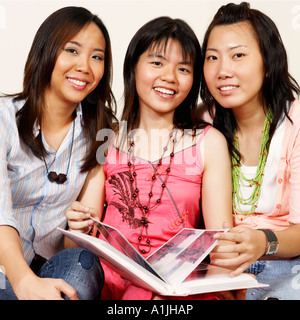 Portrait of three young women sitting together on a couch and smiling Stock Photo