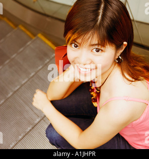 High angle view of a young woman sitting on an escalator smiling Stock Photo