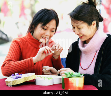 Two young women seated at a table and holding a candy Stock Photo
