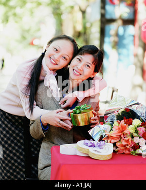 Portrait of two young women holding a gift and smiling Stock Photo