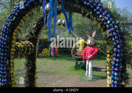 a Giant Easter Bunny is pulling a wagon full with colorful painted easter eggs Stock Photo