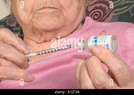 RF MR PR Close up diabetic Senior caucasion woman in pink blouse draws insulin from bottle into syringe Stock Photo