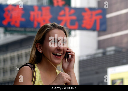 Beautiful Young Blonde Haired German Woman Laughing on a Mobile Phone in Hong Kong, China Stock Photo