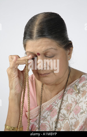 Indian senior citizen dot on forehead in sari chanting the holy name Stock Photo