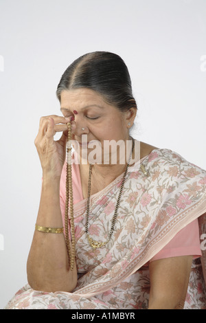 Indian old senior citizen chanting on beads - MR# Stock Photo