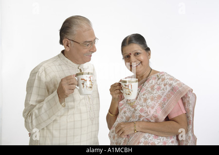 Indian senior citizen couple drinking coffee on white background Stock Photo