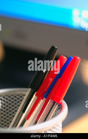 Coloured pens in container on desk top Stock Photo
