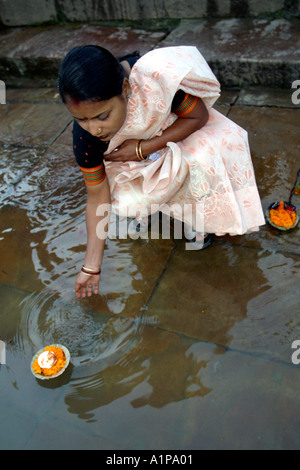 An Indian woman puts a lit candle in the water of the holy river Ganges in the city of Varanasi in northern India Stock Photo