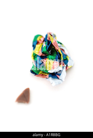 Crumpled candy wrapper and small piece of chocolate Stock Photo