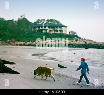 mature woman walking her dog on beach Stock Photo