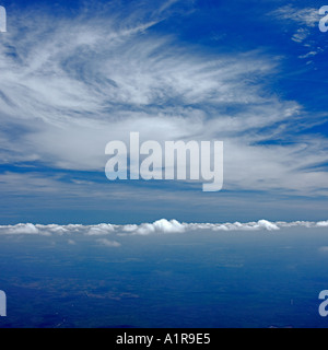 Aerial view above cumulus and below stratus cloud formations against blue sky Stock Photo