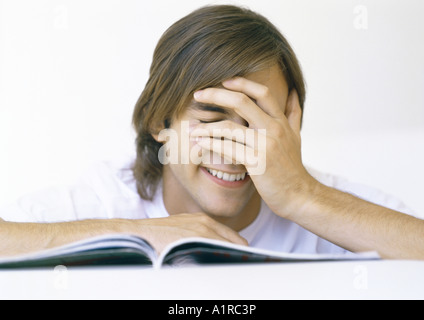 Man with book, covering face Stock Photo