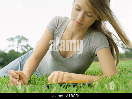 Woman lying in grass, writing Stock Photo
