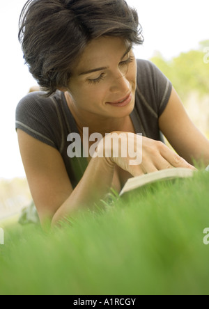 Woman lying in grass, reading Stock Photo