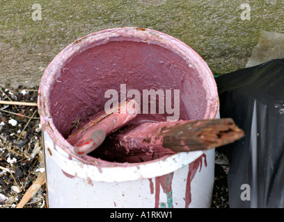 A can of pink paint with a well used brush and a mixing stick Bunbeg Harbour County Donegal Ireland Stock Photo