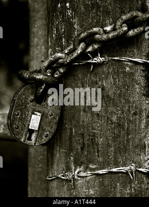 Rusty padlock on fence post in black and white Stock Photo