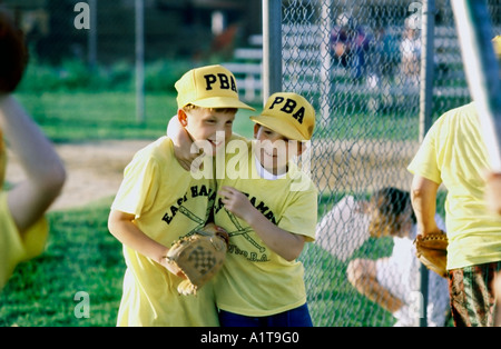 EAST HAMPTON, NY, USA, Two Young Teens, Hugging at Male Baseball Game, Children Playing Game Outside Little League Uniforms Sports Boys Stock Photo