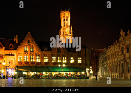 People eating in the pavement restaurants under The Belfry in the medieval town of Bruges in Belgium Stock Photo