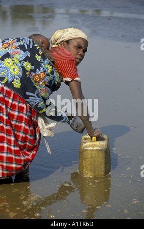 Goma, Zaire (Congo) Refugee camp, a woman with a baby on her back, collecting filthy water Stock Photo