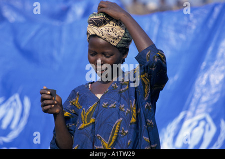 RWANDAN REFUGEES KATALE CAMP. Young woman looking at herself in a mirror in front of UNHCR tent Stock Photo