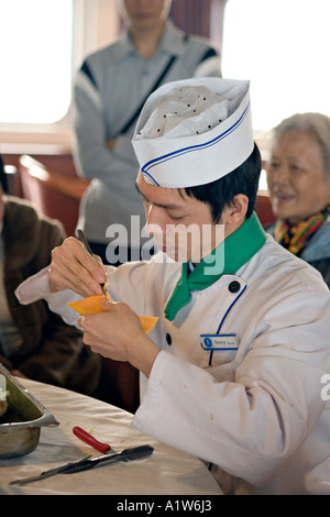 CHINA YANGTZE RIVER Chef demonstrating vegetable carving by carving a carrot to look like a shrimp Stock Photo