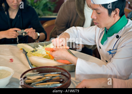 CHINA YANGTZE RIVER Chef demonstrating vegetable carving by carving a carrot to look like a shrimp Stock Photo