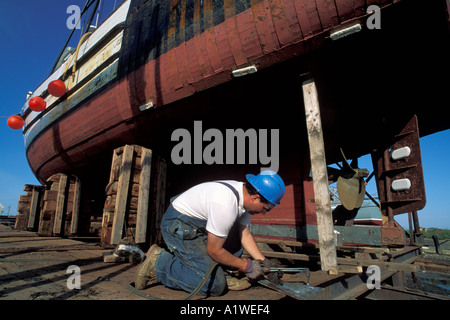 Welder working on a fishing boat in dry dock Nova Scotia Canada Stock Photo