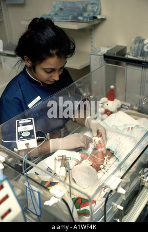 Post-natal ward with nurse tending to baby in an incubator Stock Photo