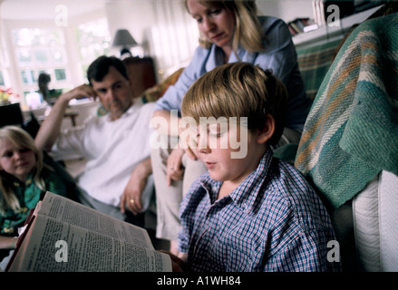 BOY READING BIBLE WITH FAMILY AT HOME Stock Photo